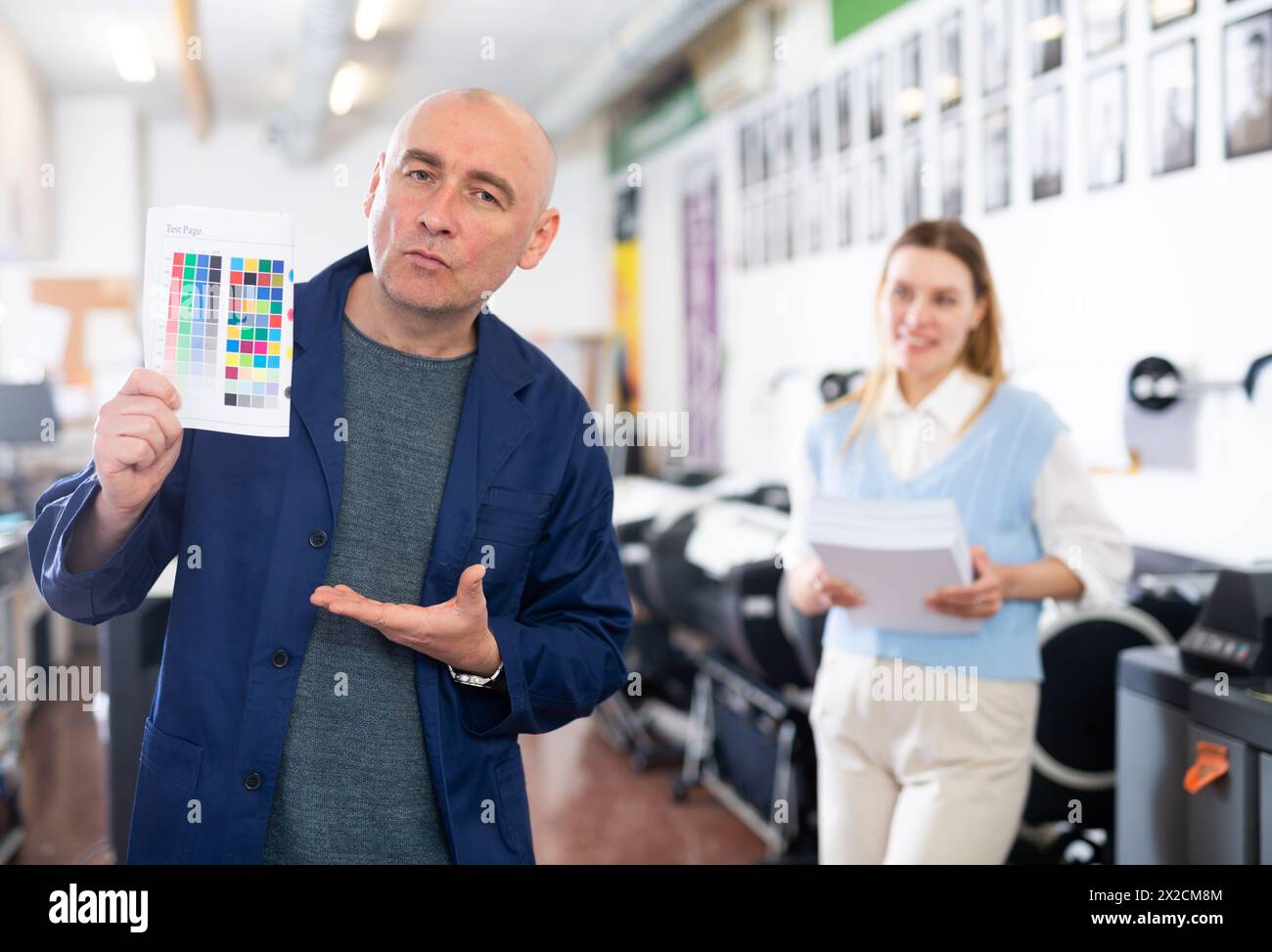Service engineer demonstrating test page with color palette in his hand ...