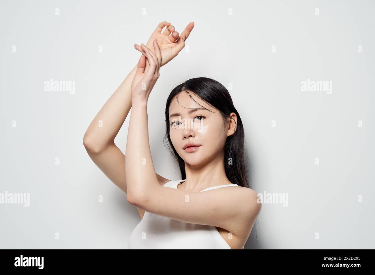 Asian Woman Poses in White Top Against White Background Stock Photo