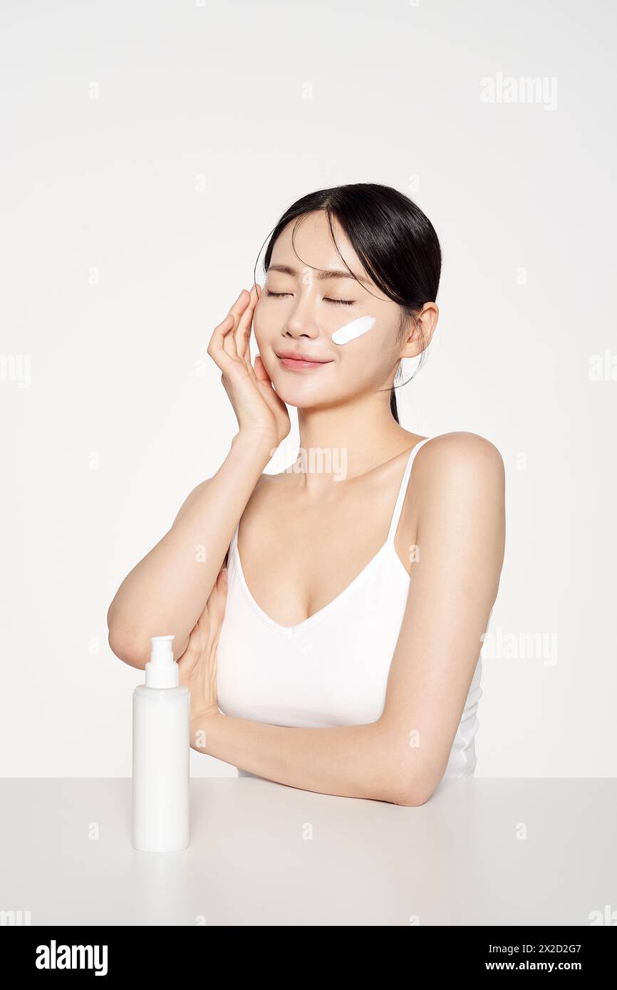 Asian Woman Poses to Apply Cosmetics to Her Face Stock Photo