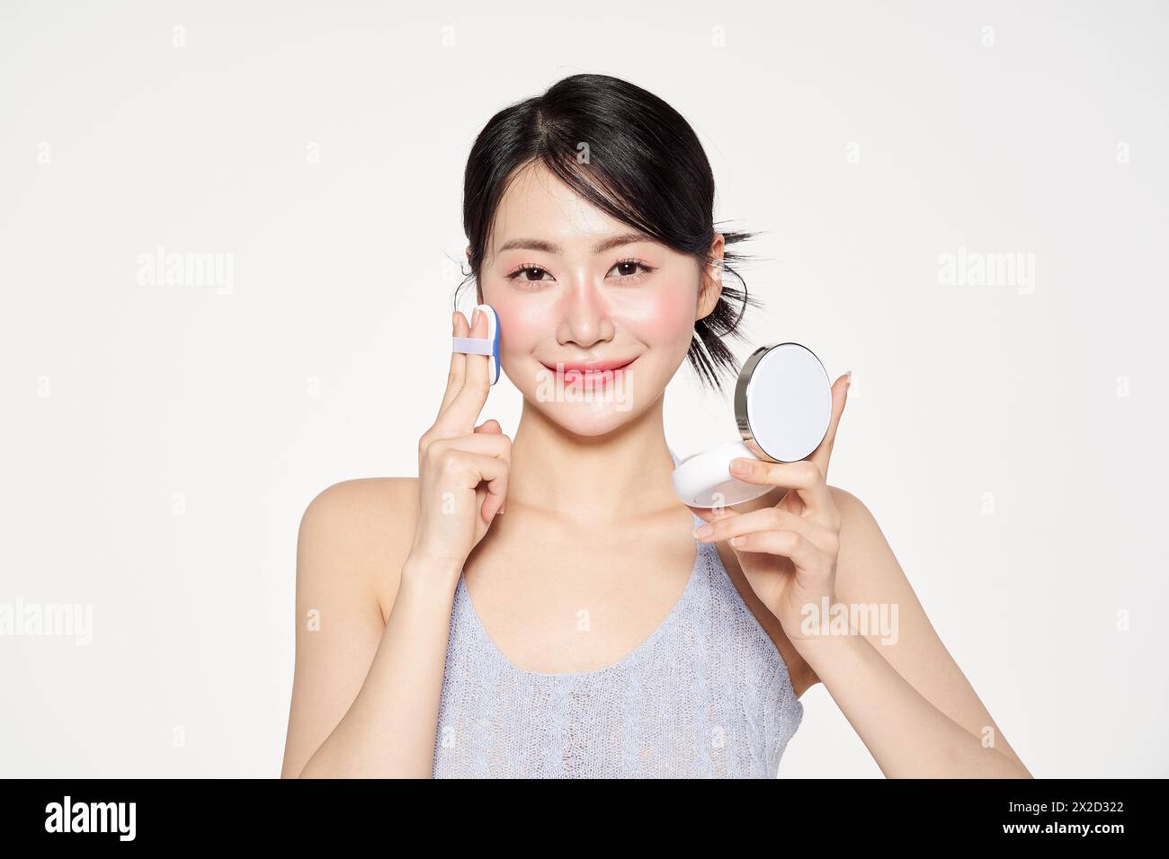 Asian Woman Putting Cushion Facts on Her Face Stock Photo