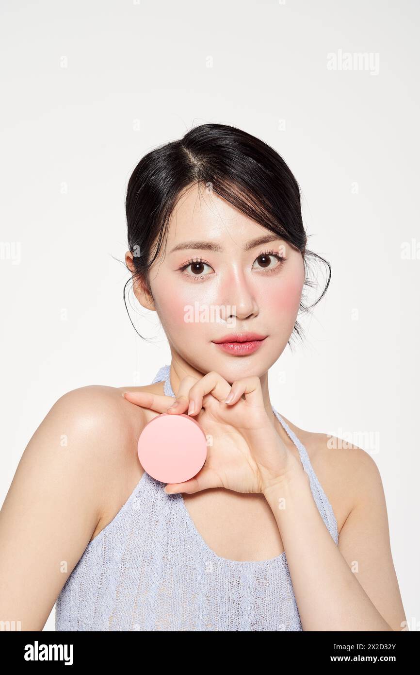 an Asian woman holding a pink cushion pact Stock Photo
