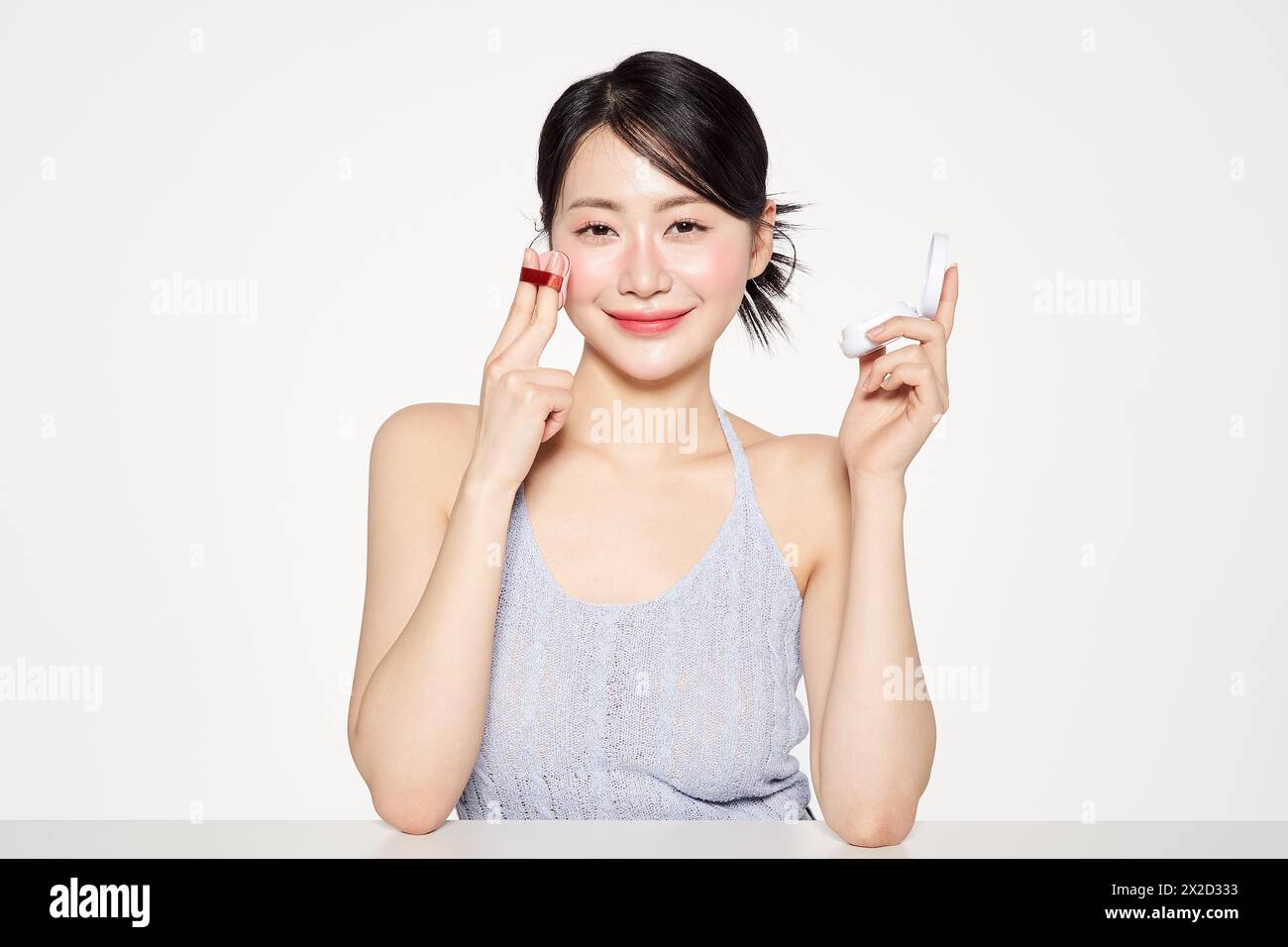 an Asian woman who applies cushion compacts to her face Stock Photo