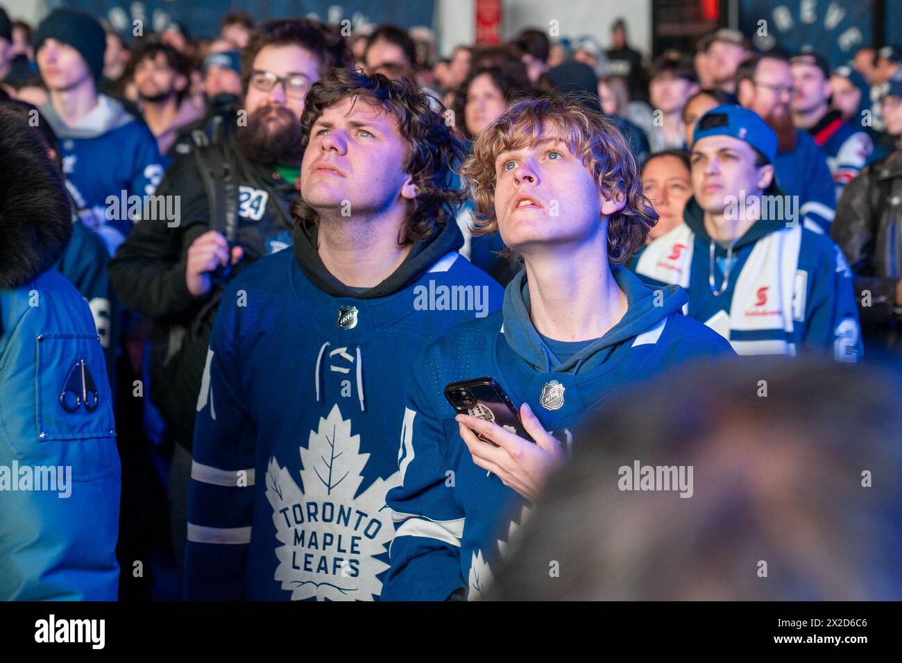 Fans watching the game on a giant screen react as the Boston Bruins score a goal against the Toronto Maple Leafs at Maple Leaf Square outside Scotiabank Arena. During Toronto Maple Leafs playoff games, Maple Leaf Square transforms into a sea of blue and white, echoing with the chants of passionate fans eagerly rallying behind their team's quest for victory. The electric atmosphere radiates anticipation and excitement, creating unforgettable memories for both die-hard supporters and casual observers alike. (Photo by Shawn Goldberg/SOPA Images/Sipa USA) Stock Photo