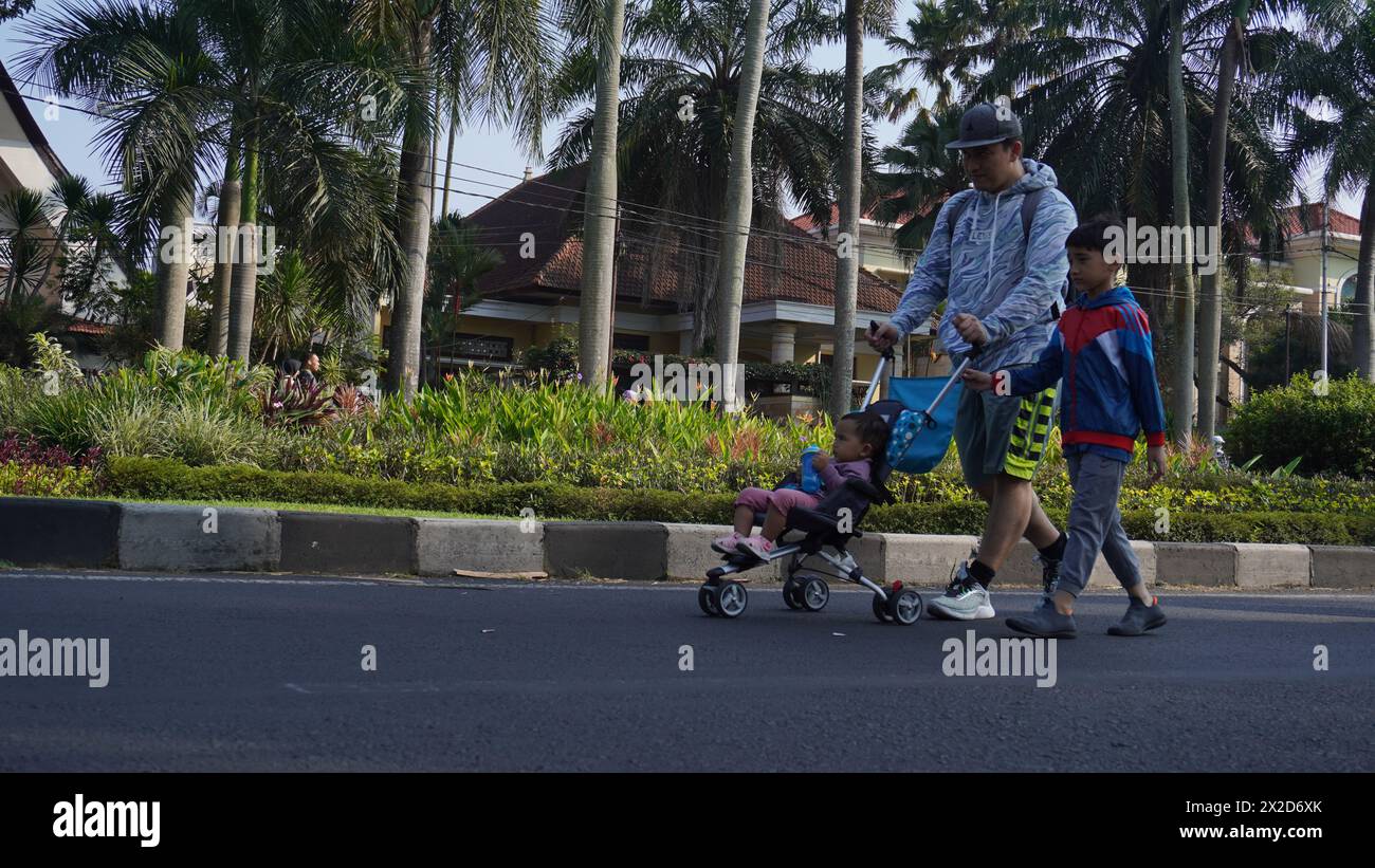 A father is walking with his son while pushing his baby child in a A father is walking with his son while pushing his baby child in a
