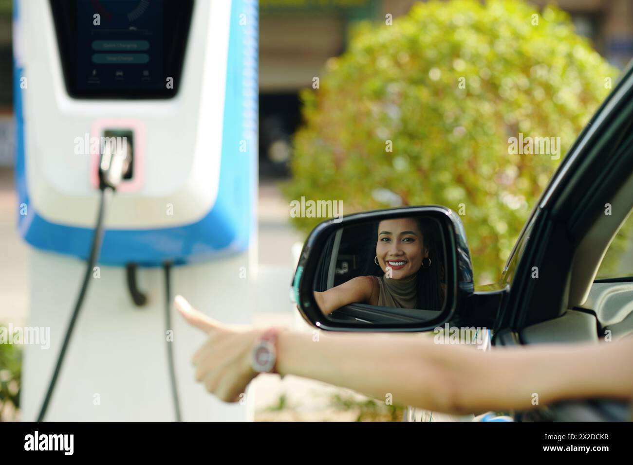 Happy ev driver showing thumbs up after charging electric car Stock ...