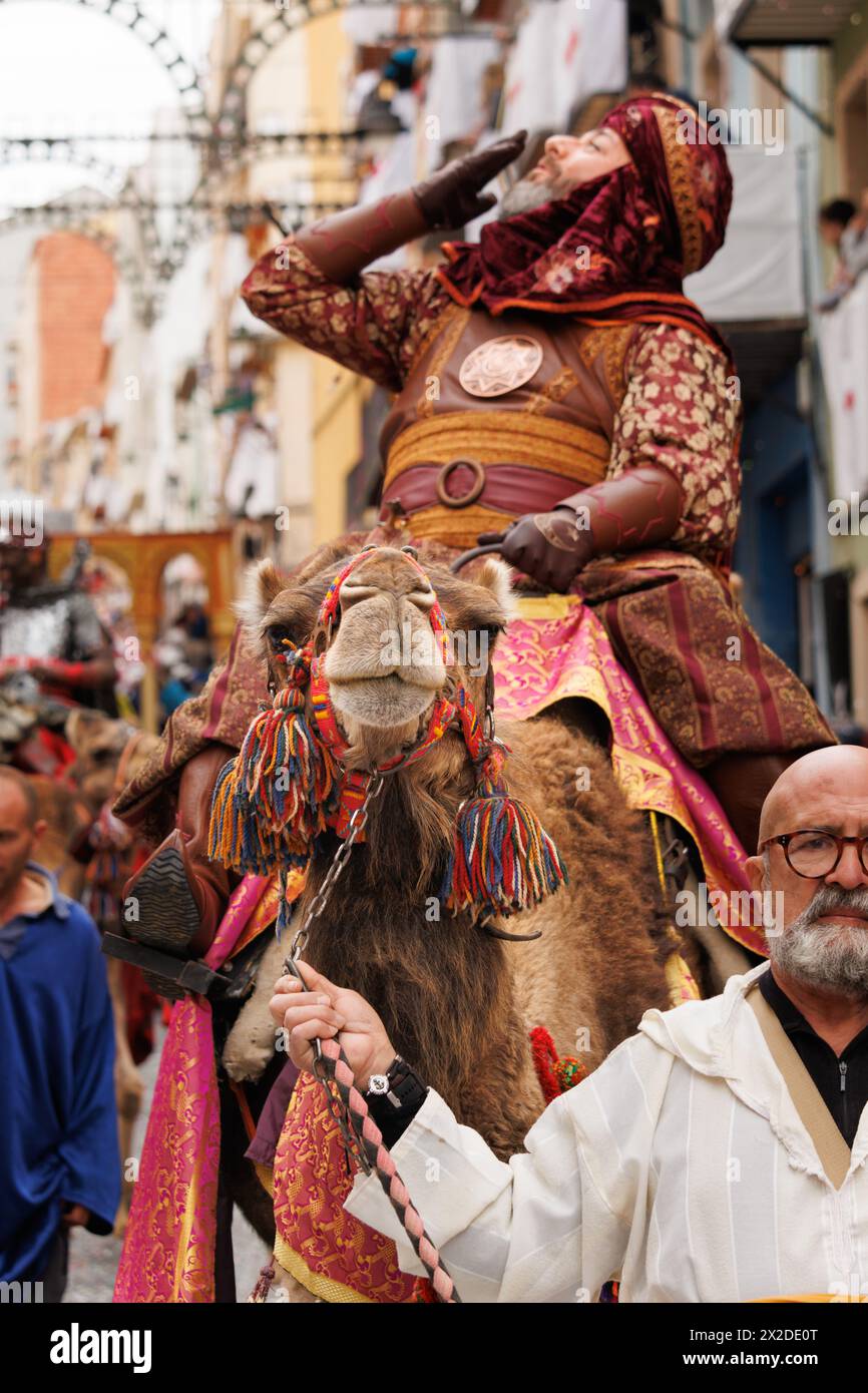 04-20-2024, Alcoy, Spain: Gentleman accompanying a dromedary from the Mudejares troupe parading through the streets of Alcoy with the spotlight on the Stock Photo