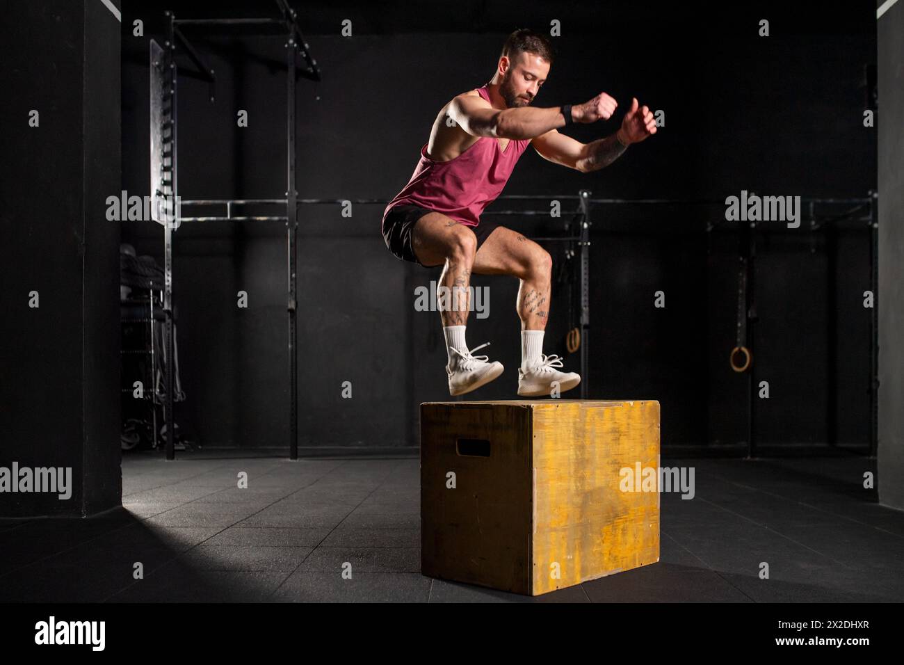 Man in sportwear jumping onto yellow box. Vertical box jumps workout. Routine workout for