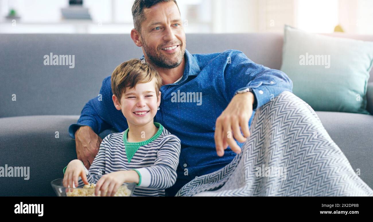 Relax, dad and son watching tv on sofa in home with popcorn, online video or streaming movie together. Film, father and child on couch for television Stock Photo