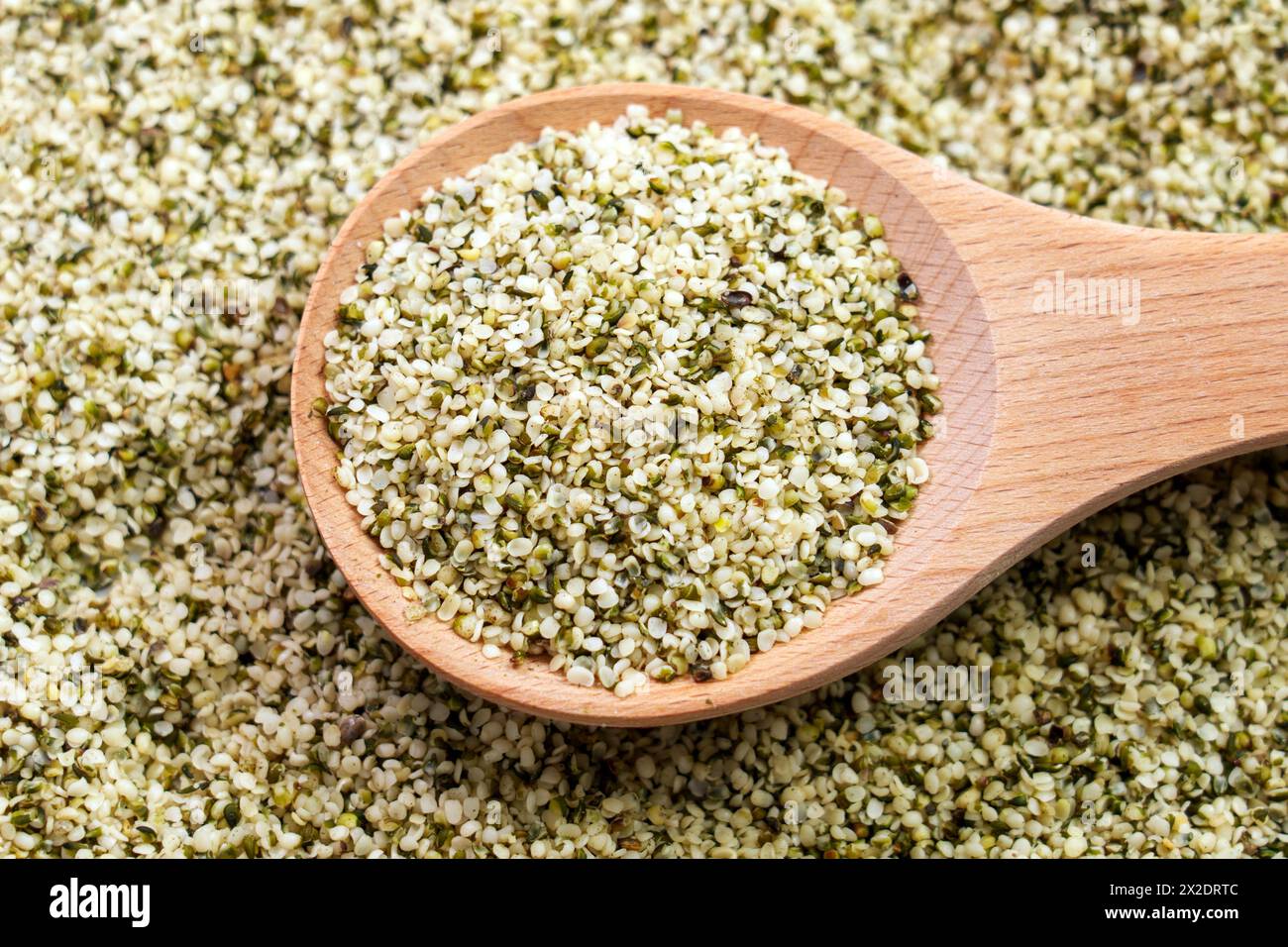 Hemp seeds in rustic wooden spoon close up. Peeled nutritious Cannabis sativa grains. Superfood ingredient. Stock Photo