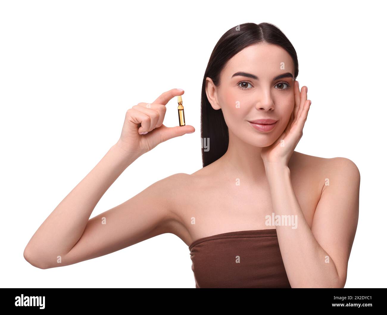 Beautiful young woman holding skincare ampoule on white background