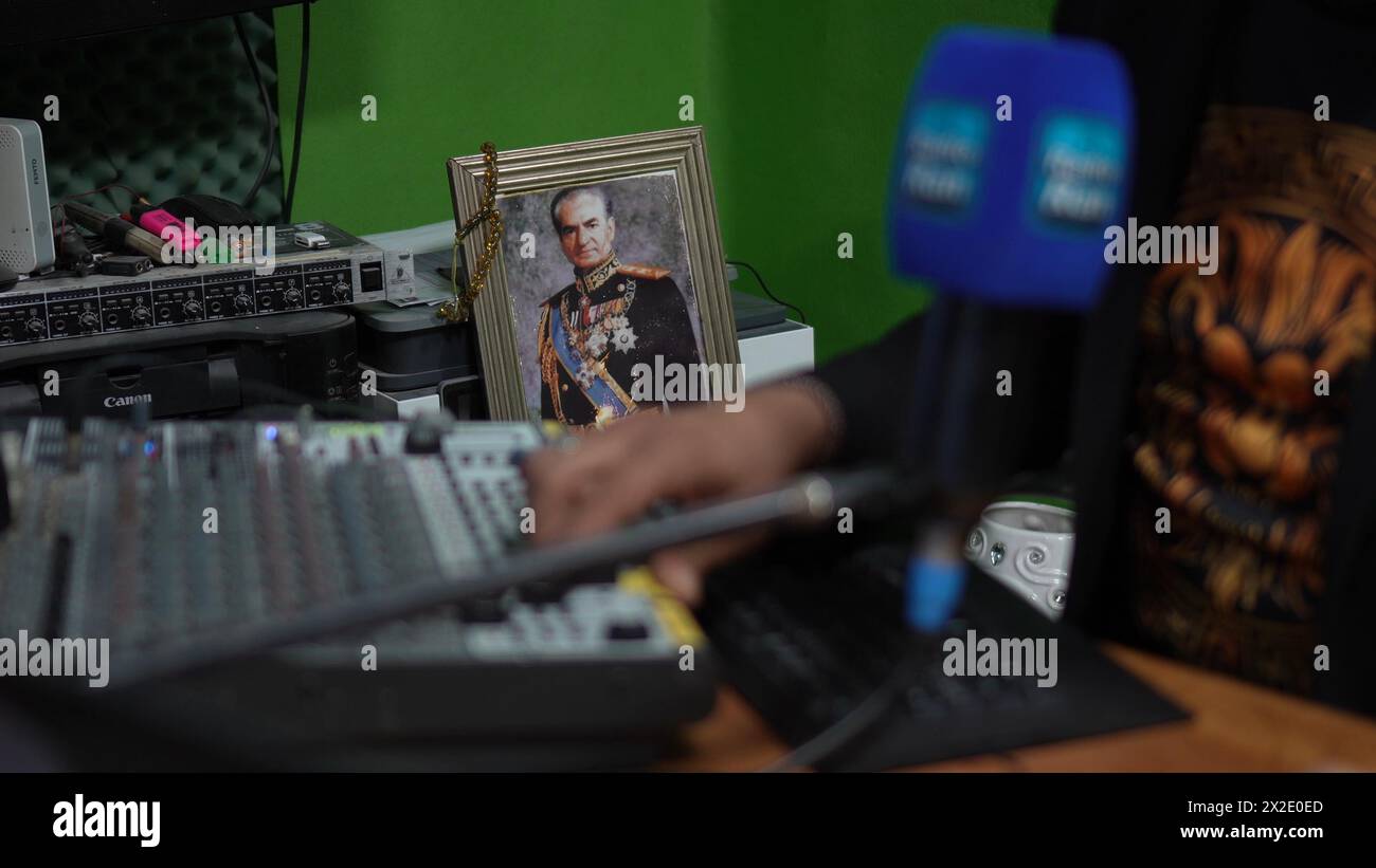 A photo of Mohammad Reza who was the shah of Iran stands at radio station Ran while its founder, Rani Amrani, speaks with an Iranian while broadcasting live on April 21, 2024 in Jerusalem. The radio station Ran, which is operated by Iranian Jews, hosts daily broadcasts that draw Farsi speakers from all over the world including from Iran. Stock Photo