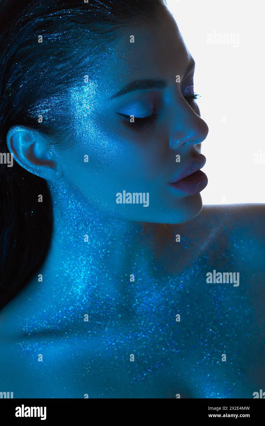 Woman beauty profile with shimmering skin is highlighted by a soothing blue glow, makeup Stock Photo