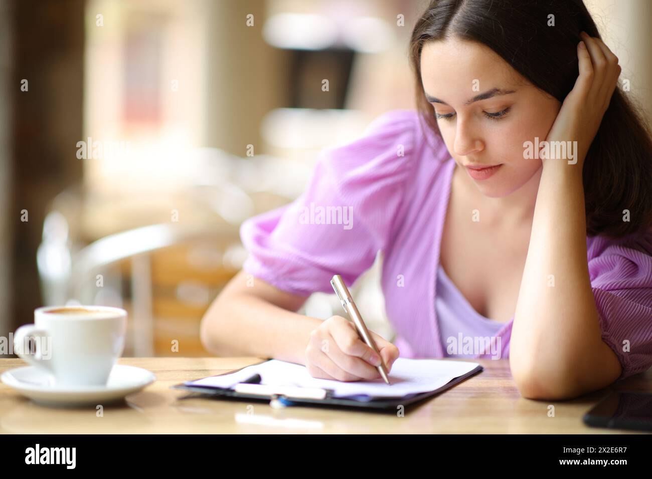 Serious woman filling form in a restaurant terrace Stock Photo - Alamy