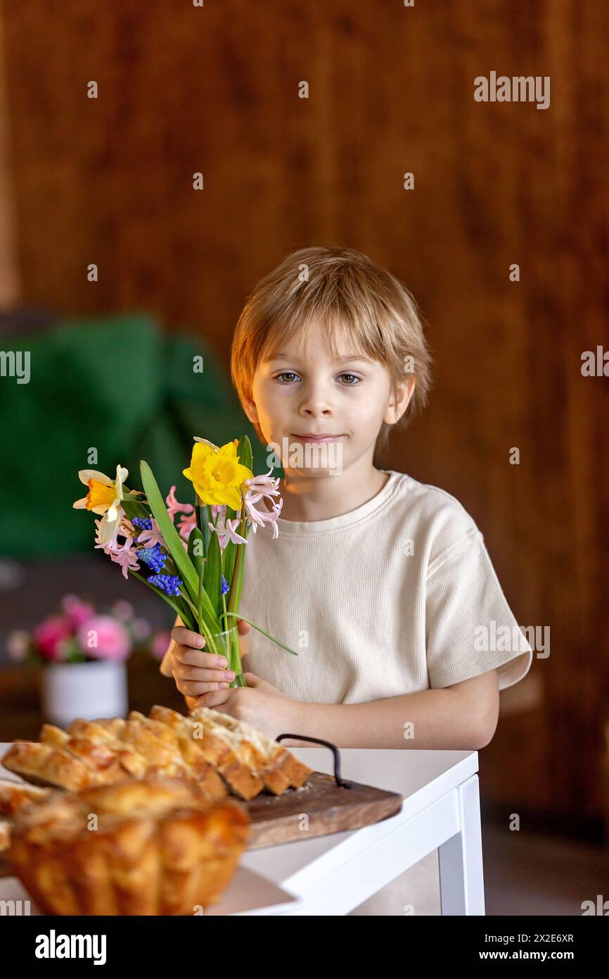 Cute preschool child, boy, holding sweet brioche bun for Easter, traditional swee bread baked with almonds, nuts and sugar, home Stock Photo