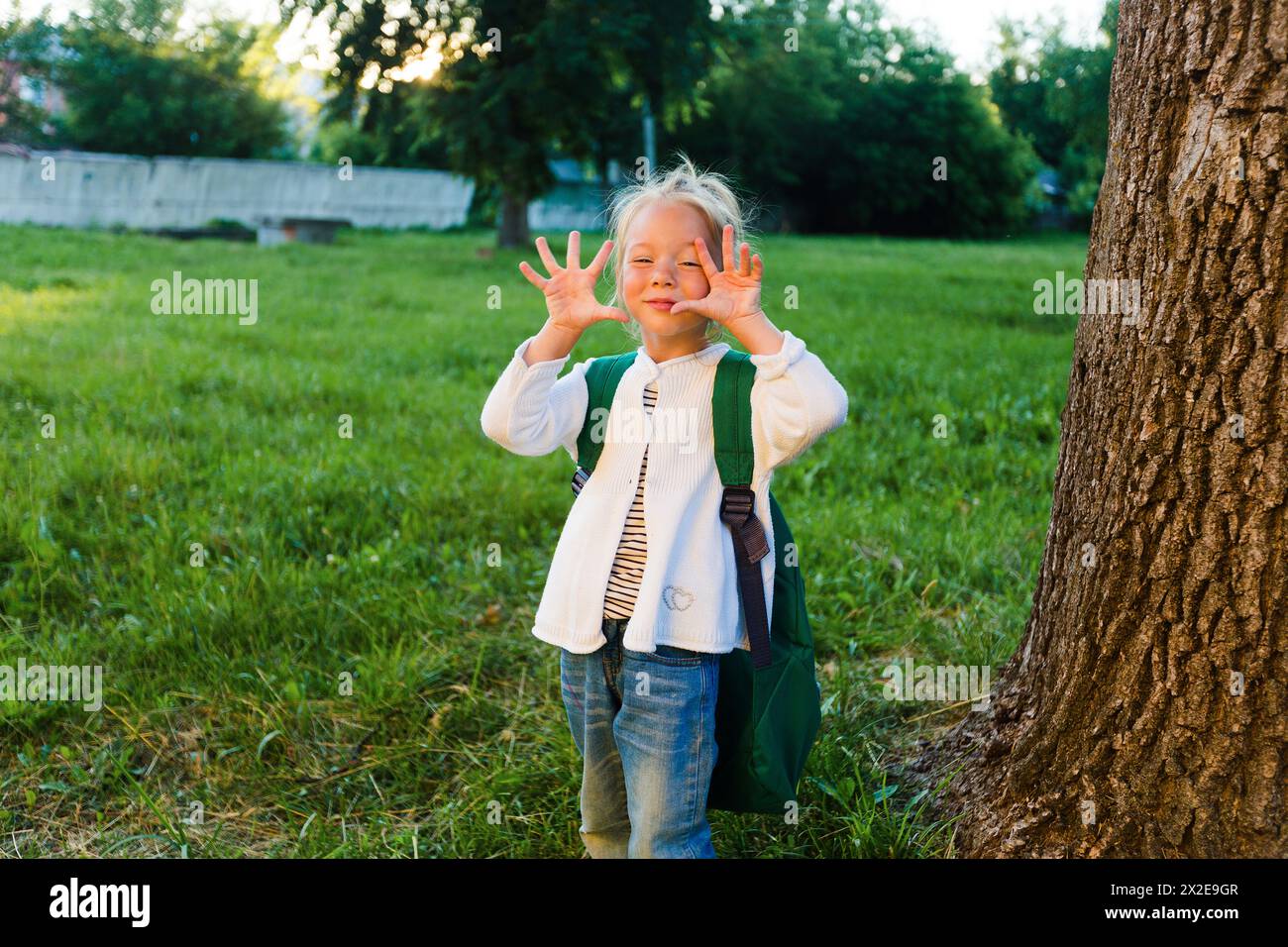 A little girl makes faces and has fun in a beautiful summer park. Stock Photo