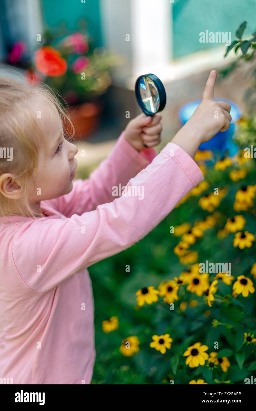 A child examines a plants under a magnifying glass Stock Photo
