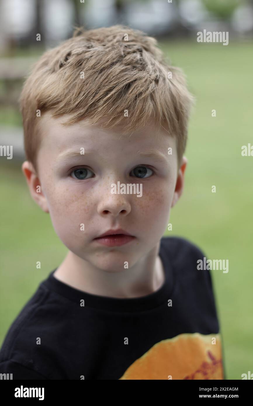 Thoughtful boy in a playful tee outdoors Stock Photo