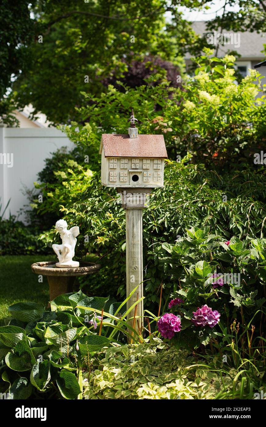 Birdhouse, bird bath, fairy statue in a garden Stock Photo
