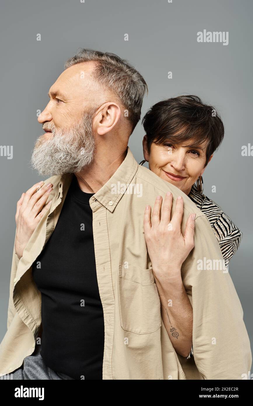 A middle-aged man and woman in stylish attire strike a pose in a studio setting for a fashionable portrait. Stock Photo