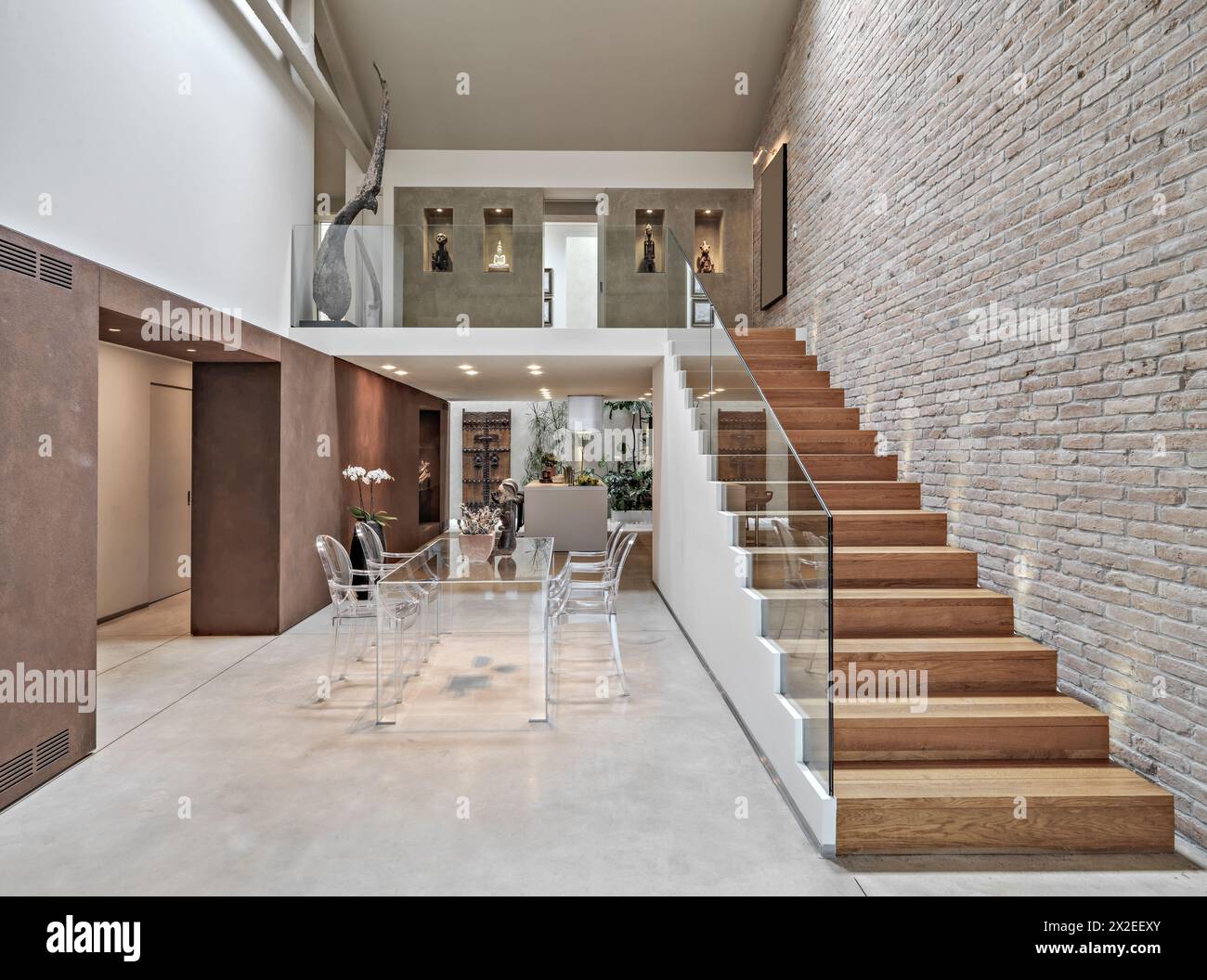 interior shots of a modern loft, in foreground the dining table with its chairs to whose right there is a wooden staircase the walls are covered of br Stock Photo