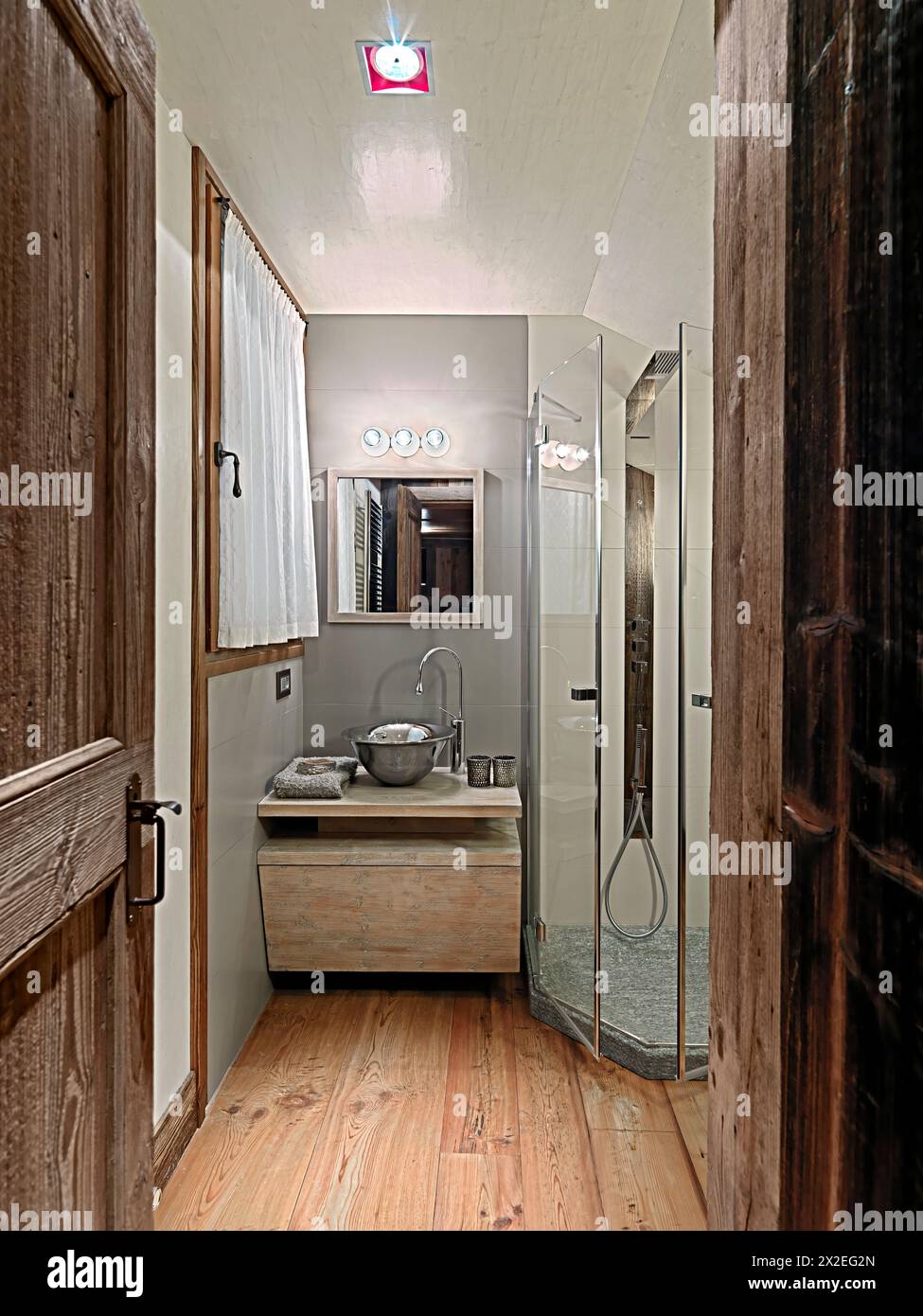 rustic bathroom interior with wooden floor on the background the washbasin cabinet with a countertop washbasin and its mirrro on the right can you see Stock Photo