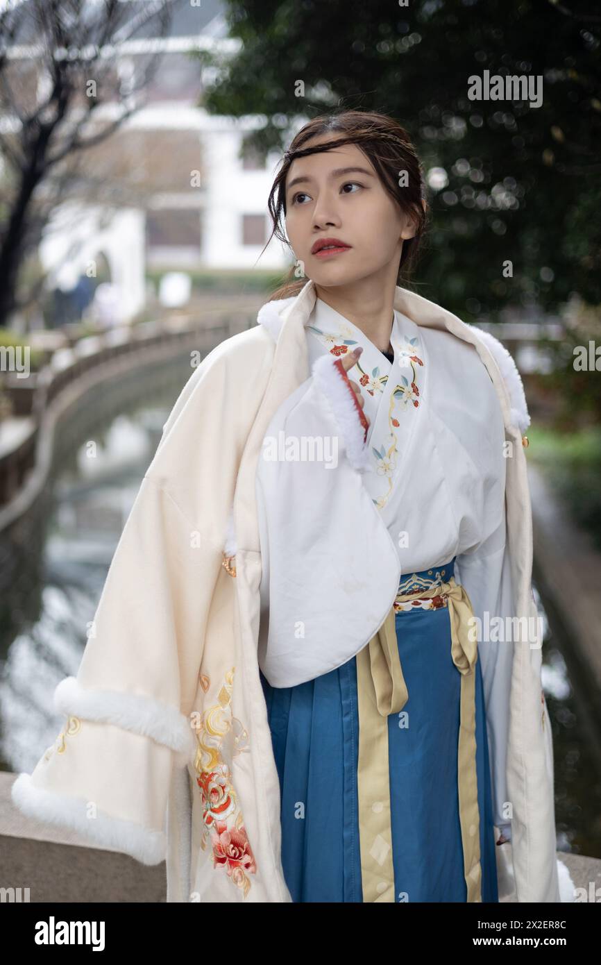 A beautiful Chinese woman wearing a traditional dress and coat in Suzhou, China Stock Photo