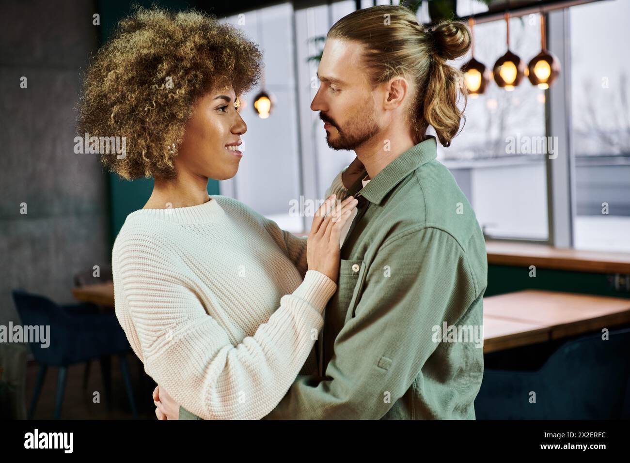 African American woman and man stand side by side, looking out a cafe window, creating a romantic silhouette. Stock Photo