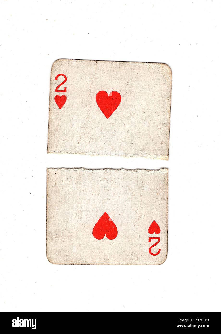 A vintage, well used two of hearts playing card torn in half on a white ...