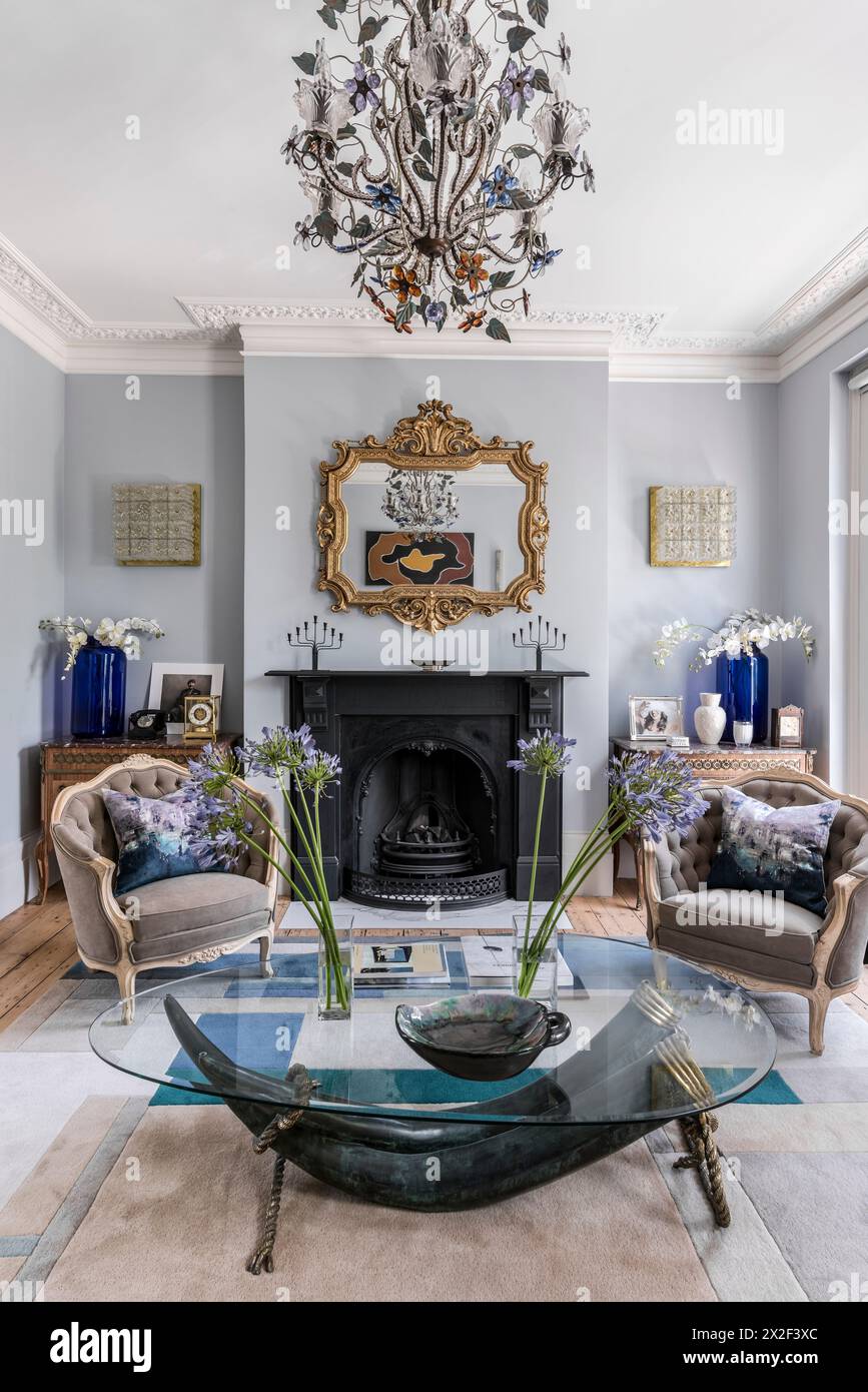 Antique gilt framed mirror above fireplace with beige armchairs in Georgian townhouse, Paultons Square, Chelsea, London, UK. Stock Photo