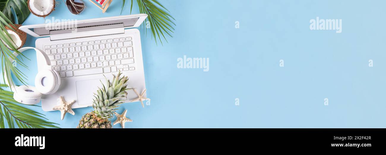 Work and vacation. Creative summer beach office flat lay with white laptop, tropical summer accessories, palm tree leaves, sunglasses, flip flops, pin Stock Photo