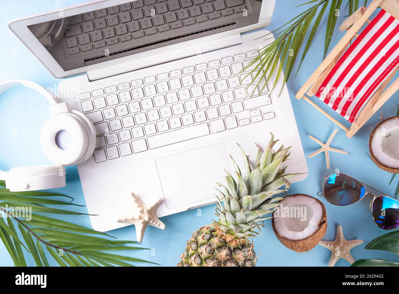 Work and vacation. Creative summer beach office flat lay with white laptop, tropical summer accessories, palm tree leaves, sunglasses, flip flops, pin Stock Photo