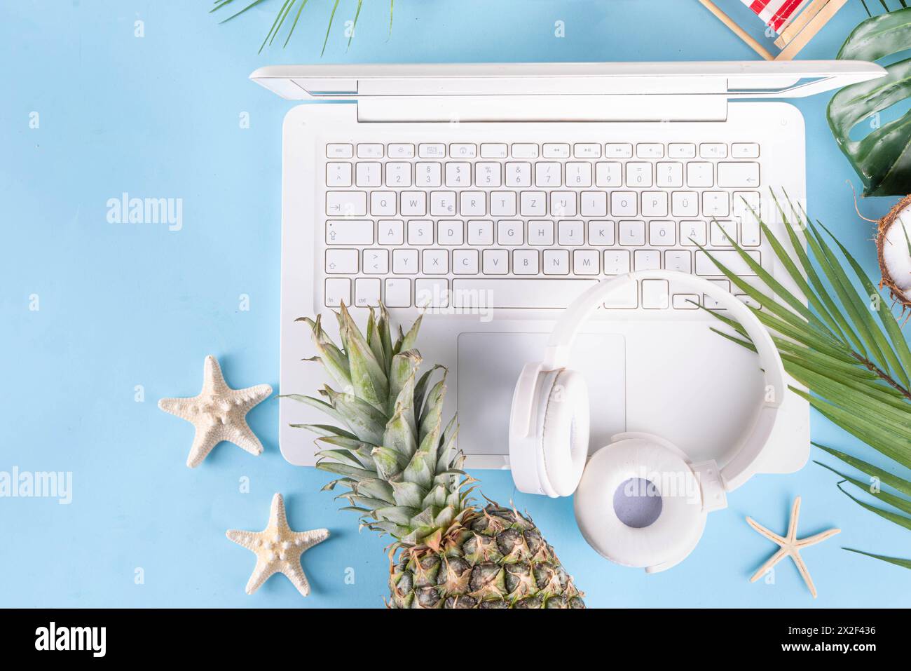 Work and vacation. Creative summer beach office flat lay with white laptop, tropical summer accessories, palm tree leaves, sunglasses, flip flops, pin Stock Photo