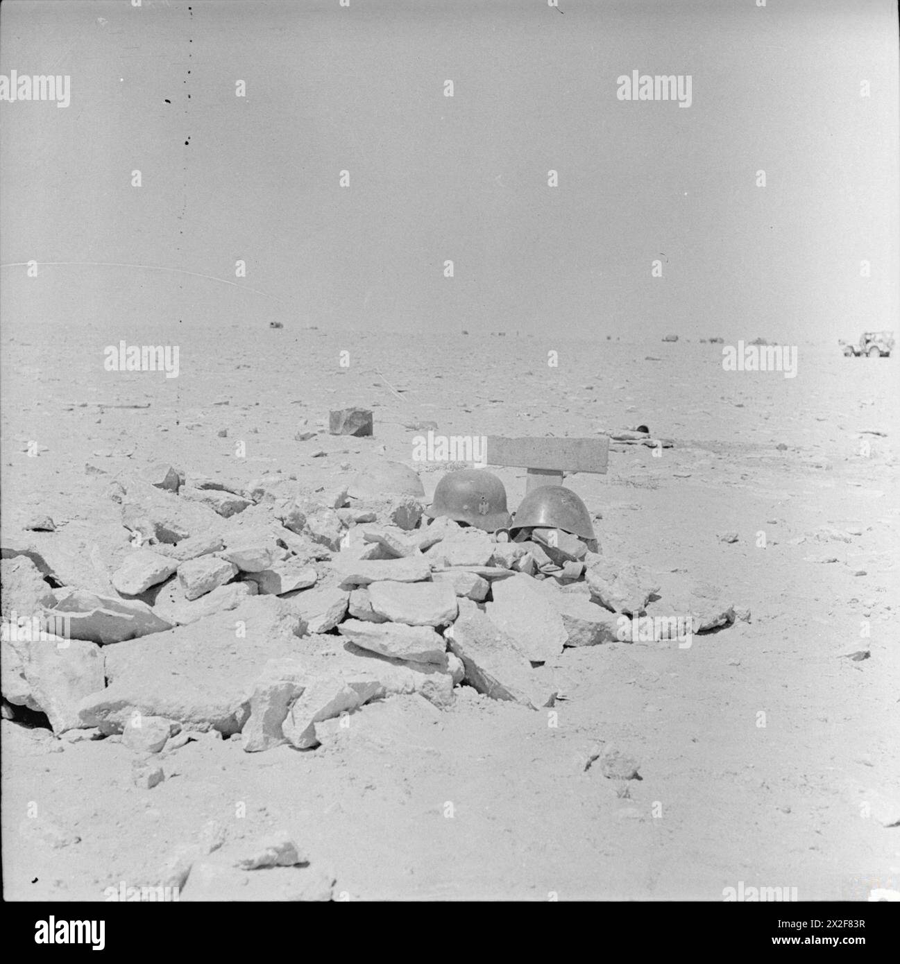 FURTHER MISCELLANEOUS PICTURES OF BATTLE ACTIVITIES SOUTH OF EL ALAMEIN - A desert grave where lie buried a British Tommy side by side with a German and an Italian soldier. At the head of the grave are their respective tin hats Stock Photo