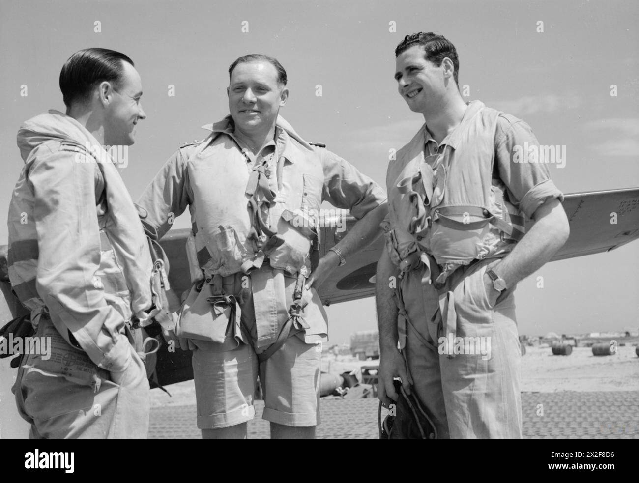 ROYAL AIR FORCE: ITALY, THE BALKANS AND SOUTH-EAST EUROPE, 1944-1945. - Colonel L A Wilmot SAAF, Commanding Officer of No. 239 Wing RAF (centre), standing with two of his pilots at Cutella, south of Vasto, Italy, the day after leading the Wing on a highly successful strike to the Pescara River dam, which they destroyed with 500-lb bombs, and from which all aircraft returned safely. Standing with Colonel Wilmot are the pilots whose bombs first breached the dam walls; Flight Lieutenant K Richards of No. 3 Squadron RAAF (left), and Flight Sergeant A Duguid of No. 260 Squadron RAF (right) Royal Ai Stock Photo