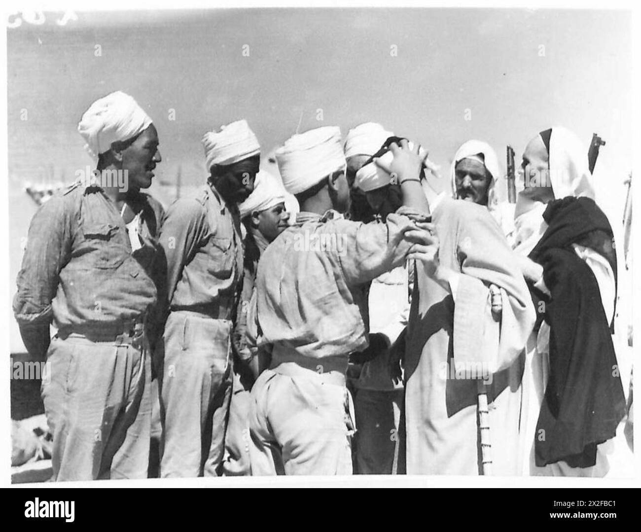 VISIT TO ITALIAN PRISONER OF WAR CAMP - A Libyan prisoner kissing the turban of Sayed Idris British Army Stock Photo