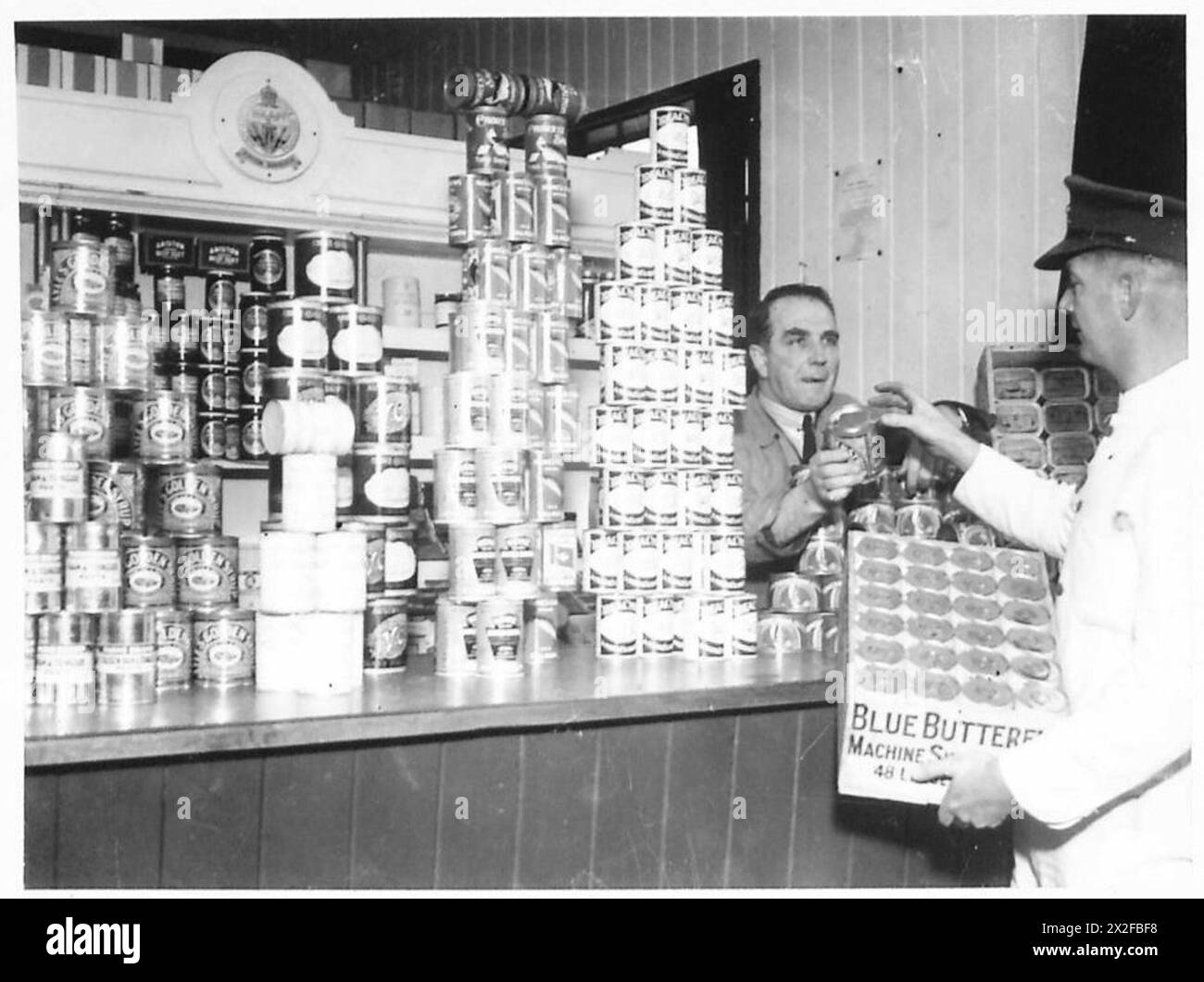 SARDINE TINS TO TANKS - NAAFI Grocer's shop in Limitary Camp issuing tin stores to Sergeant Cook British Army Stock Photo