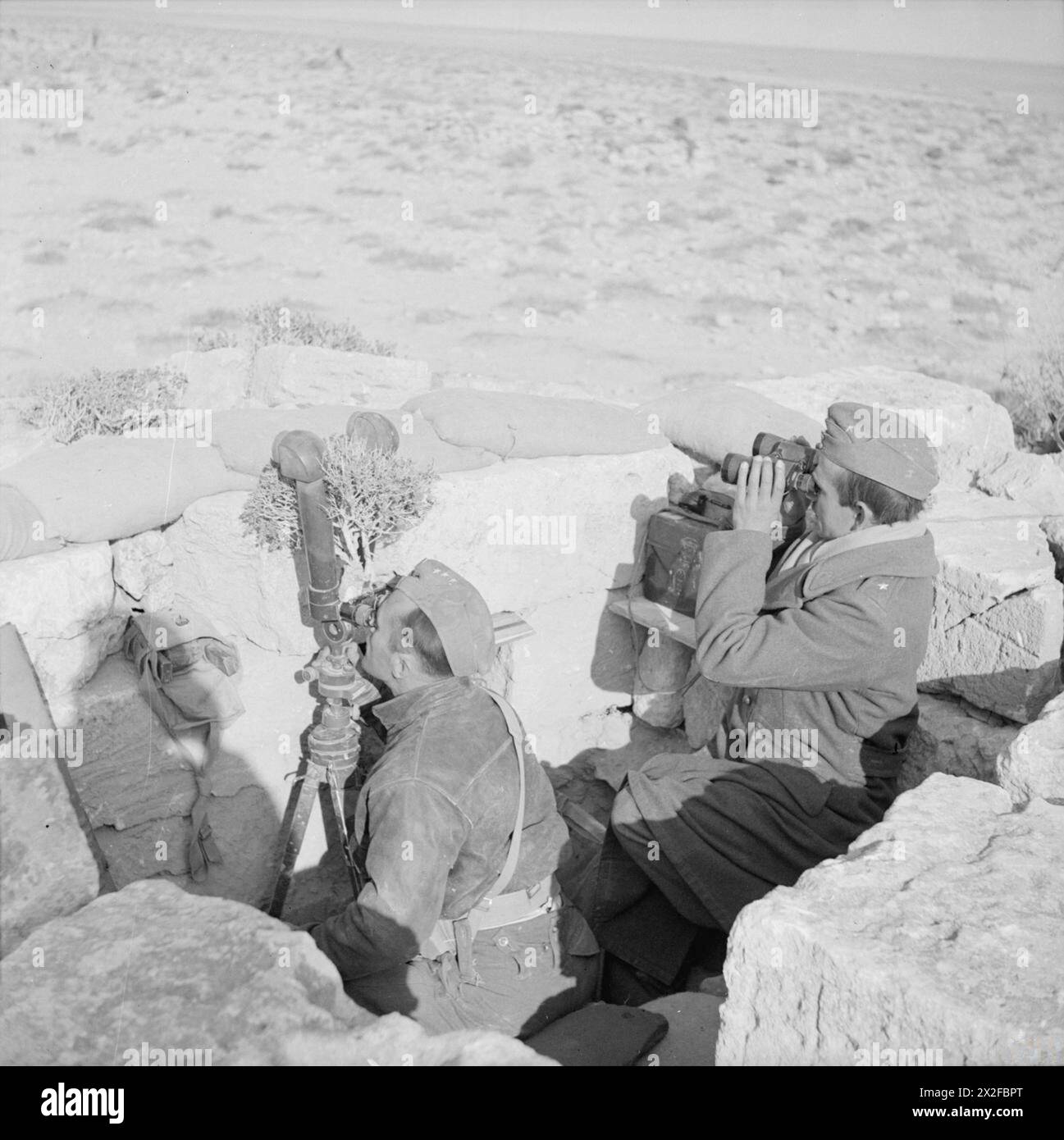 THE POLISH ARMY IN THE WESTERN DESERT CAMPAIGN, 1940-1942 - An Observation Post of the Carpathian Artillery Regiment located in the ruins of an old Greek temple, 16 February 1942. Both officers (Captain and Second Lieutenant) are looking out for the enemy, the one on the left using scissors binoculars. These pictures taken at the extreme forward positions around Carmuset er Regem (Karmusat ar Rijam) area near Gazala, show infantry and artillery units of the Polish Independent Carpathian Rifles Brigade facing German and Italian forces British Army, Polish Army, Polish Armed Forces in the West, Stock Photo