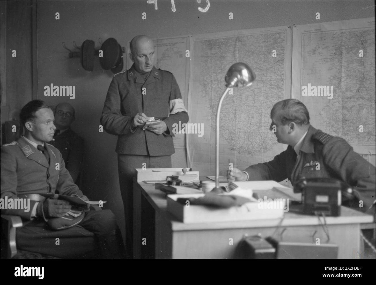ROYAL AIR FORCE: BRITISH AIR FORCES OF OCCUPATION, 1945. - Wing Commander W W Russell (right), Commanding Officer of an RAF Disarmament Wing at Stavanger, Norway, conducts a morning conference with the Luftwaffe officer (left) in charge of prisoners who are disarming German aircraft at Sola airfield. A German interpreter stands in the middle taking notes and instructions Royal Air Force, British Air Forces of Occupation, German Air Force (Third Reich) Stock Photo