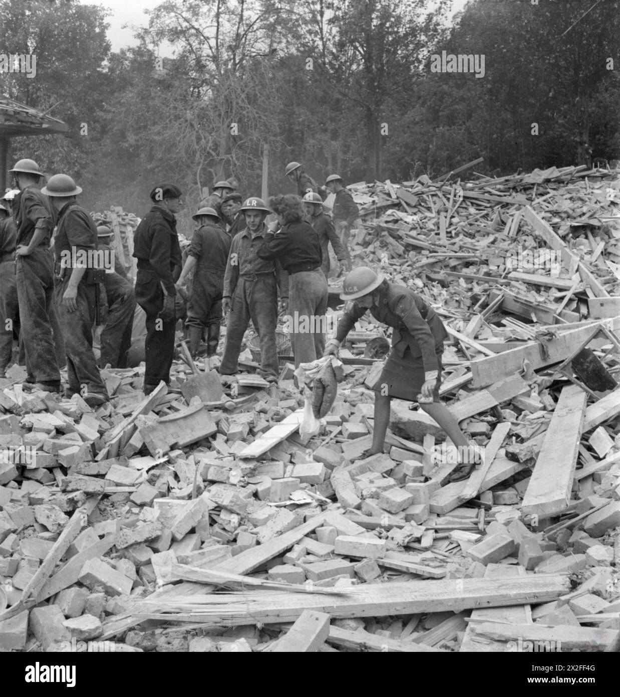 Civil Defence and American Ambulance personnel collect personal belongings and search rubble in Upper Norwood after a V1 bomb attack in 1944, London. Stock Photo