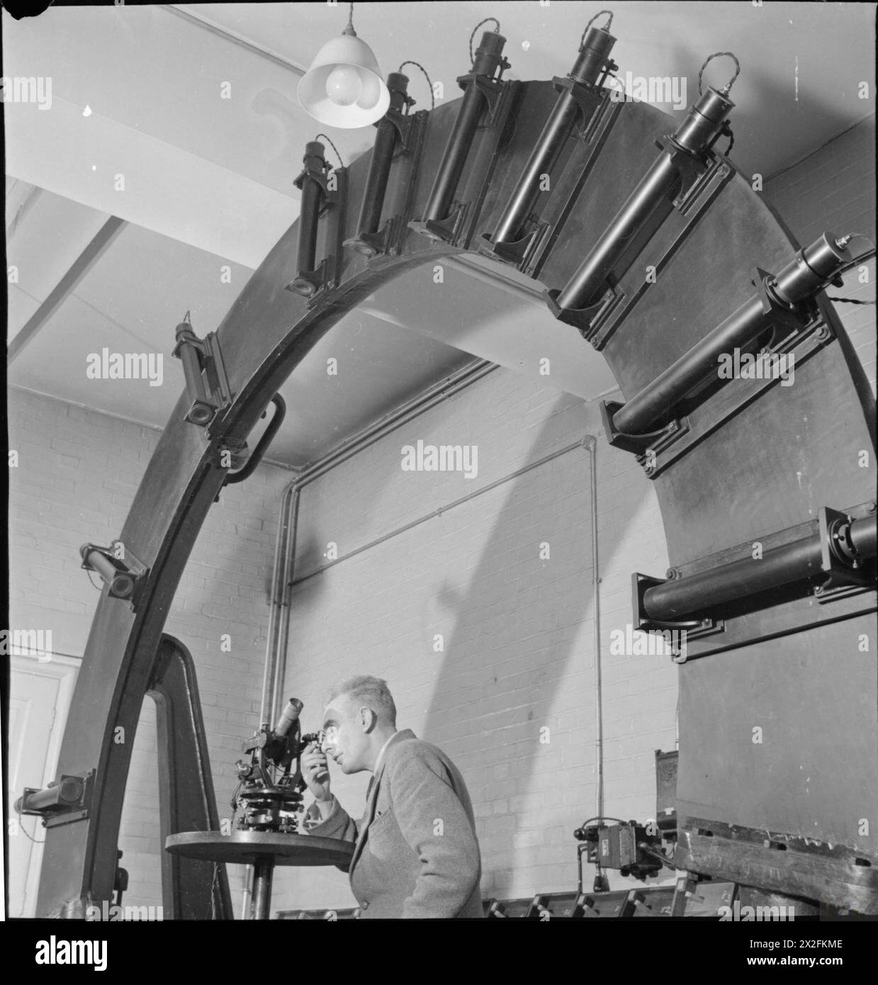 NATIONAL PHYSICAL LABORATORY: SCIENCE AND TECHNOLOGY IN WARTIME, TEDDINGTON, MIDDLESEX, ENGLAND, UK, 1944 - In the Optics Section of the Light Division at the National Physical Laboratory in Teddington, a scientist tests the angular scale of a sextant using a large wheel-like piece of apparatus, which is arranged vertically for economy of space Stock Photo