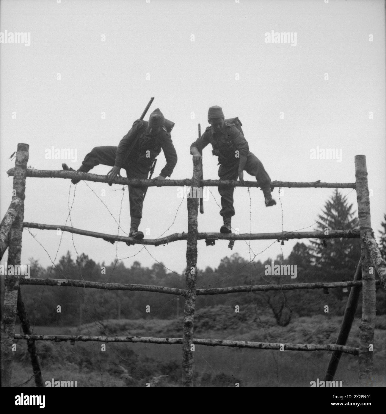 THE FREE FRENCH ARMY IN THE UNITED KINGDOM 1939-1945 - French commando troops undergoing training at Achnacarry House in Scotland: Free French troops climbing over a high obstacle from which they have to jump onto boggy ground on the assault course Free French Army Stock Photo