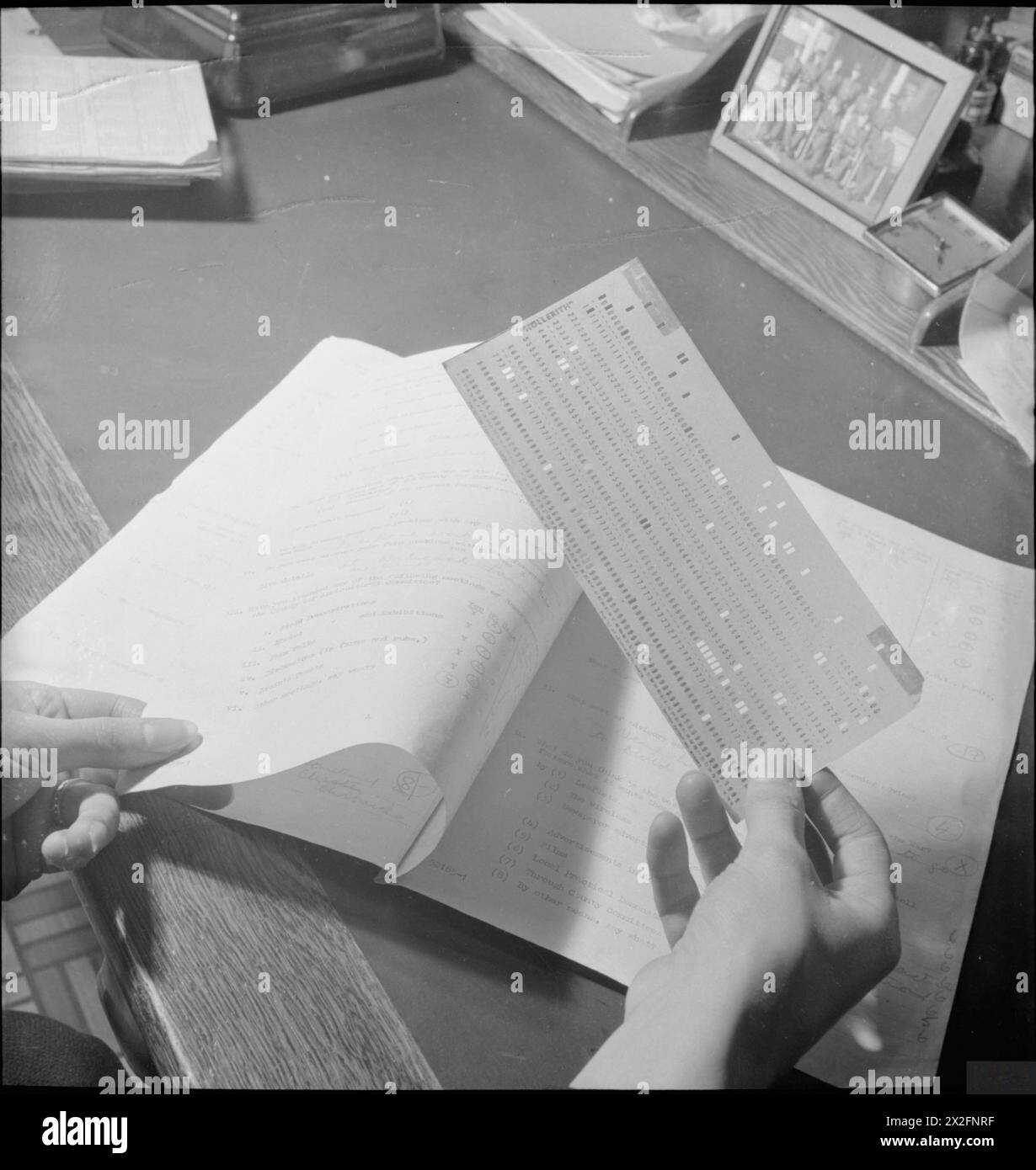 WARTIME SOCIAL SURVEY: INFORMATION GATHERING IN WARTIME BRITAIN, UK, 1944 - The information which has been gathered by interviewers arrives at the Wartime Social Survey as a series of ringed answers to questions on questionnaires. These answers are given code numbers which are then transferred to punched cards, with each hole representing the code number for a particular answer Stock Photo