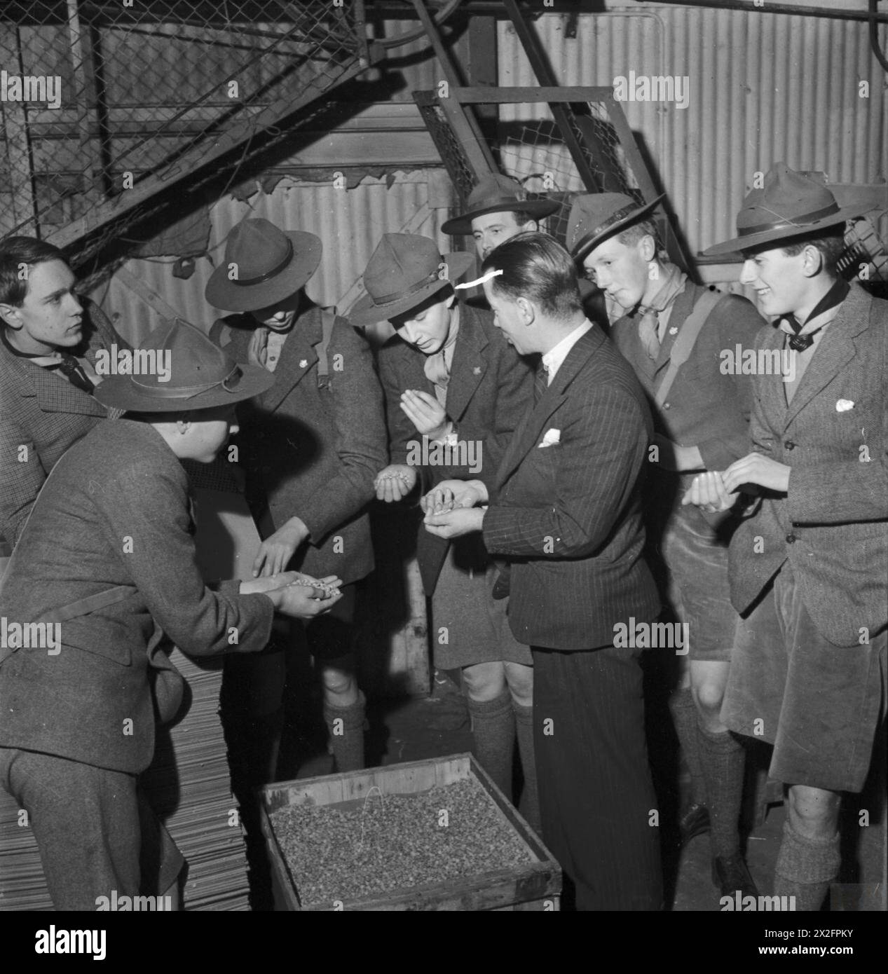 SALVAGE IN WARTIME BRITAIN: BOY SCOUTS VISIT A PAPER MILL, UK, 1943 - A group of Boy Scouts from Eton College are shown cartridge wads during their visit to a paper mill, somewhere in Britain. Members of the Boy Scout Movement played a huge part in the paper salvage campaigns across the country during the War Stock Photo
