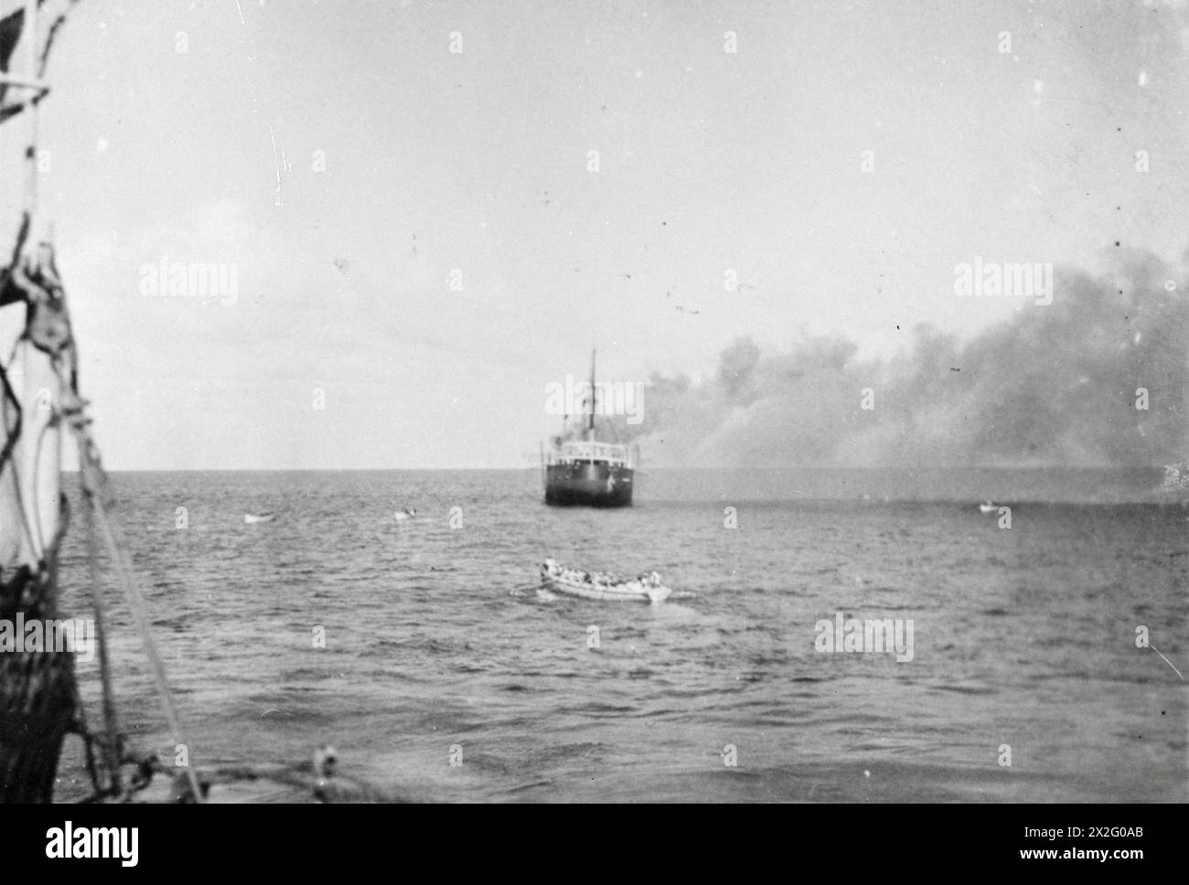 THE INTERCEPTION AND SCUTTLING OF THE GERMAN SS IDARWALD. 8 AND 9 DECEMBER 1940, ON BOARD A BRITISH WARSHIP OFF CUBA. THE GERMAN HAMBURG-AMERIKA FREIGHTER IDARWALD WAS INTERCEPTED BY A PATROLLING BRITISH WARSHIP OFF CUBA. THE GERMAN CREW AT ONCE SCUTTLED THEIR SHIP, SET FIRE TO HER, AND TOOK TO THEIR BOATS. THE BRITISH SHIP FOUGHT THE FIRE AND TOOK THE IDARWALD IN TOW, BUT SHE HAD TO BE CAST OFF SHORTLY THEREAFTER AND SANK. - The boarding vessel from the British warship is pulling towards the burning and sinking freighter Stock Photo