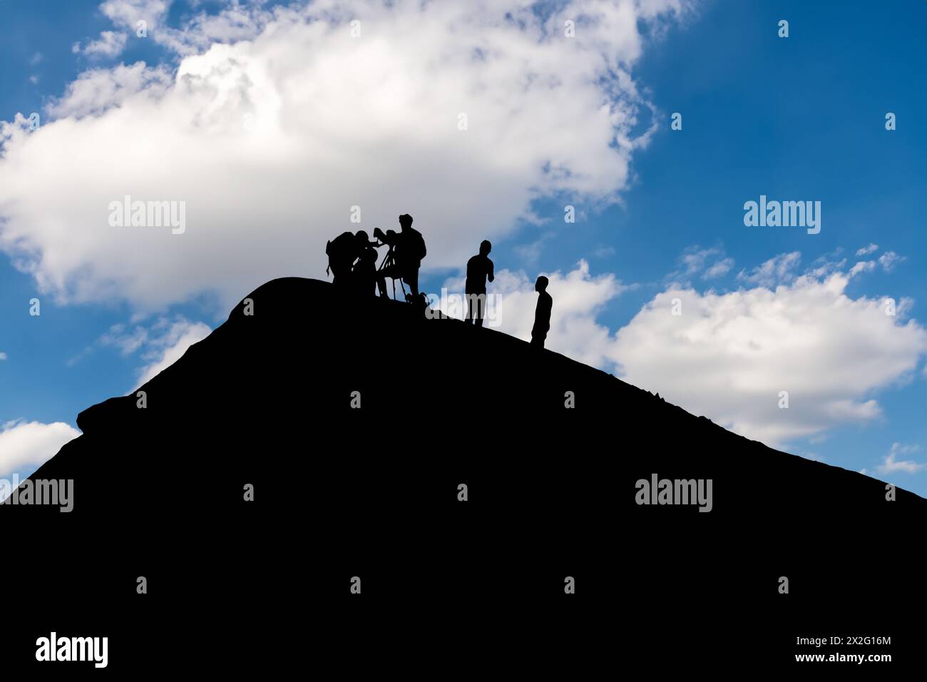 Silhouetted team conducting volcano research during picturesque sunset backdrop Stock Photo