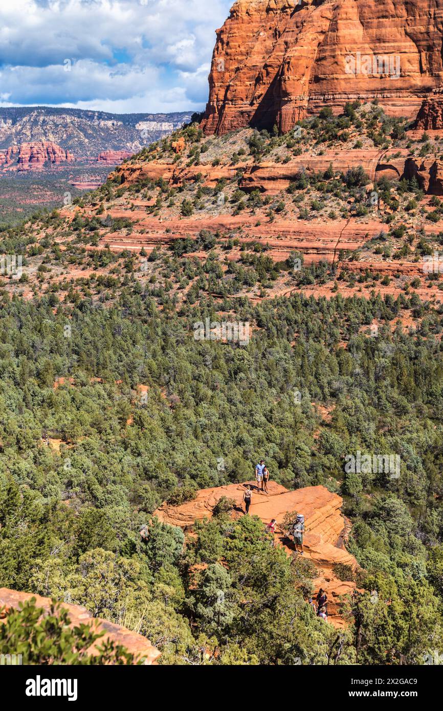 Hikers climb to the top of a red rock sandstone formation along the Devil's Bridge Trail in Sedona, Arizona Stock Photo