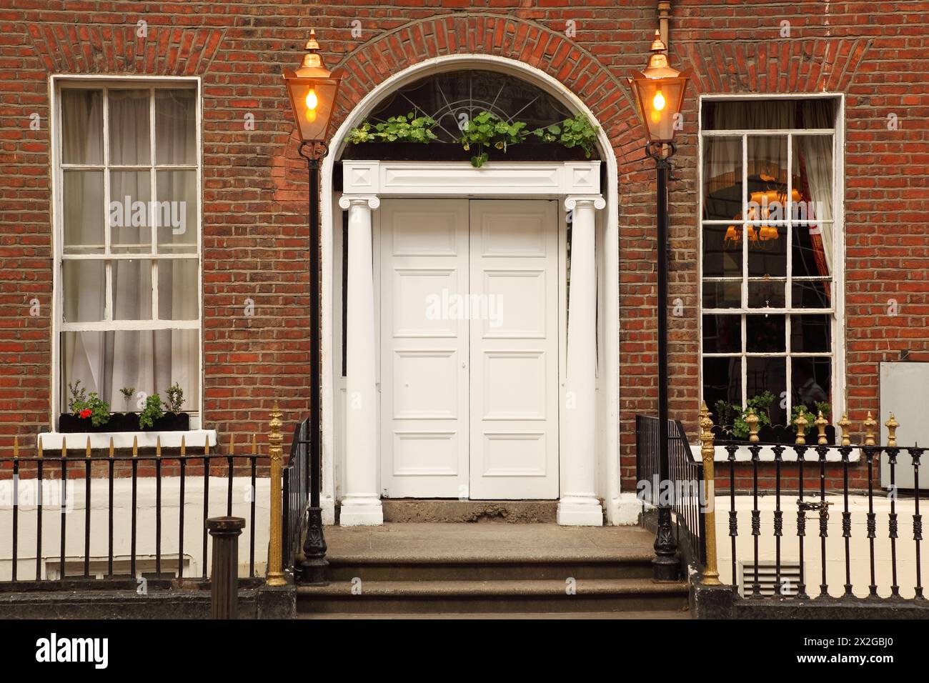 first floor and entrance to beautiful building, white door, two windows Stock Photo