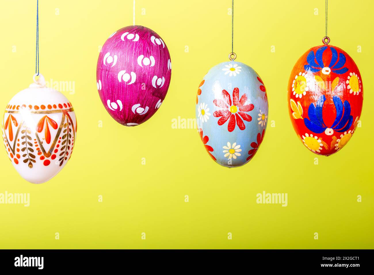 Hand painted easter eggs hanging against a yellow background Stock Photo