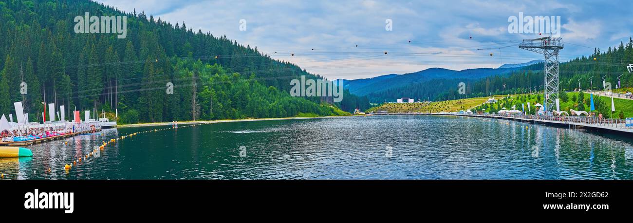 Panorama of the twilight Molodist Lake with aqua park and tower and zip line of zip bike tours, Bukovel, Carpathians, Ukraine Stock Photo