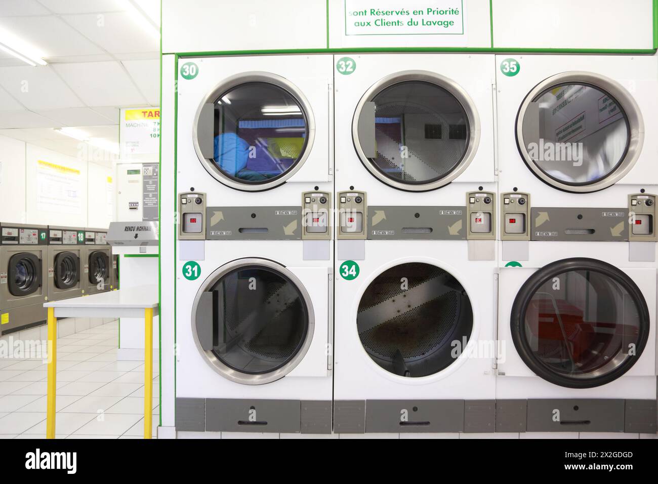number of white and gray washing machines in empty public laundry Stock Photo
